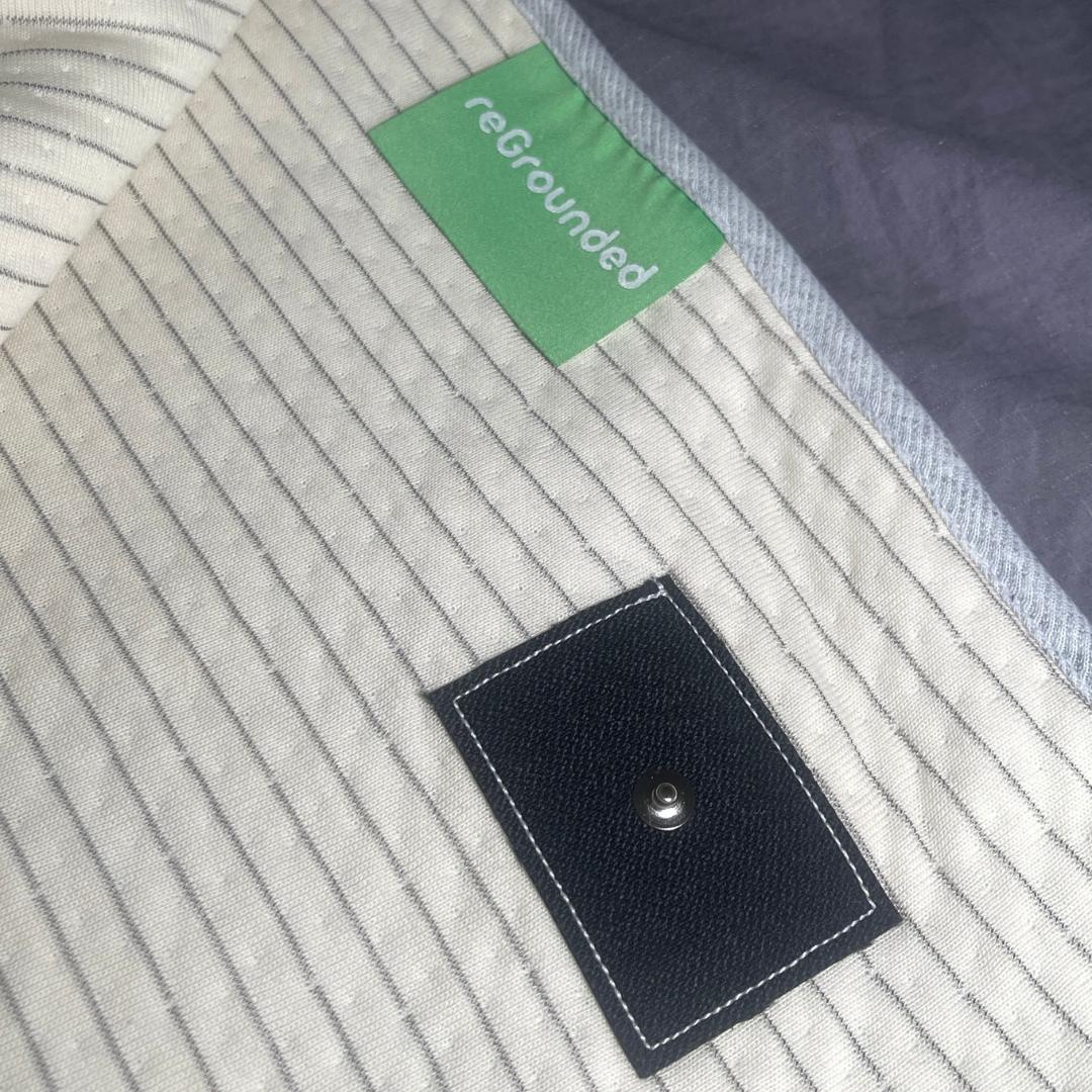 Close-up of grounding blanket fabric showing reGrounded tag and snap connection for grounding cord.