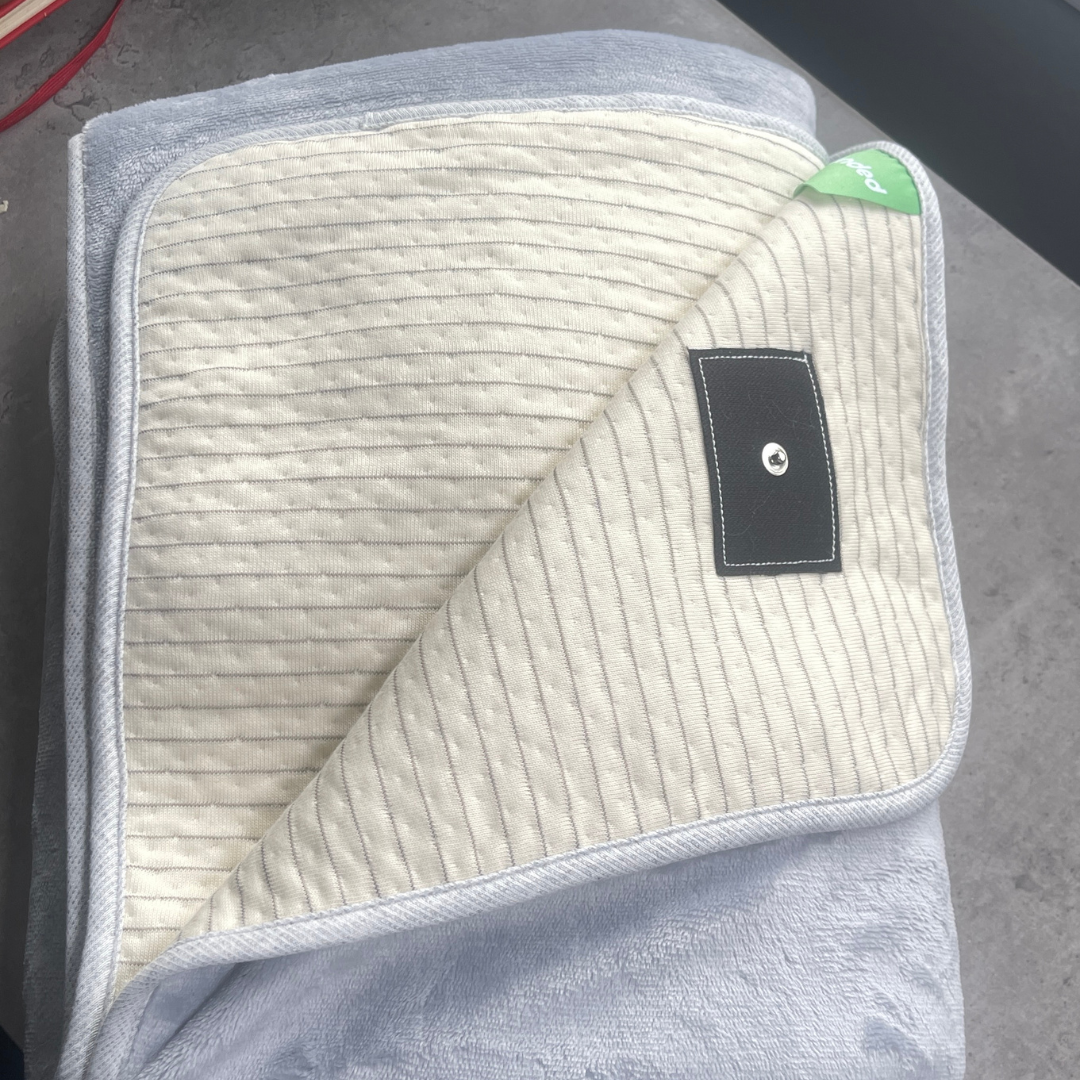 Grounding blanket folded to show soft interior lining and grounding connector tab.