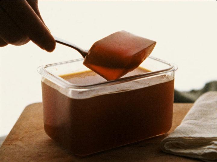 A spoon lifting set, wobbling bone broth jelly from a glass container