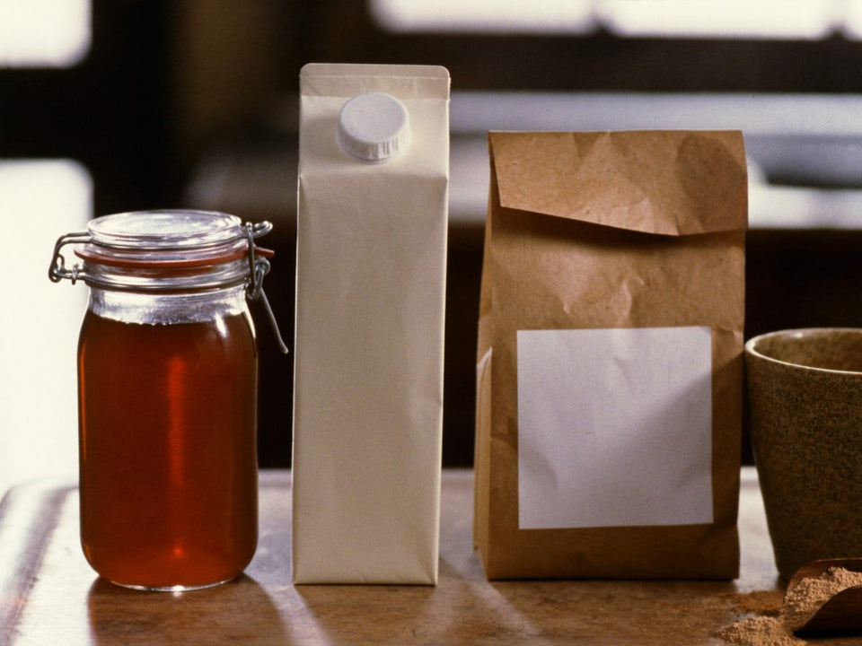 A jar of liquid bone broth, a plain carton and a pouch of bone broth powder on a worktop