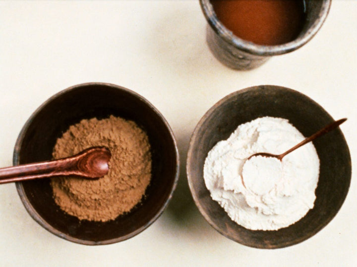 Two small bowls side by side, one of tan bone broth powder and one of white collagen powder