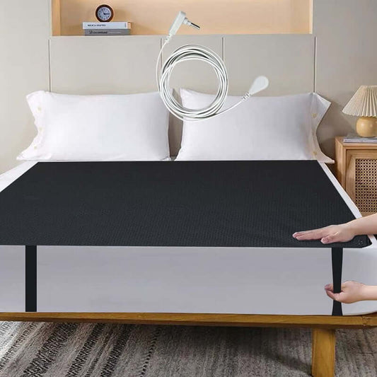 Grounding mat stretched over mattress with user hand adjusting fit – shows everyday use.
